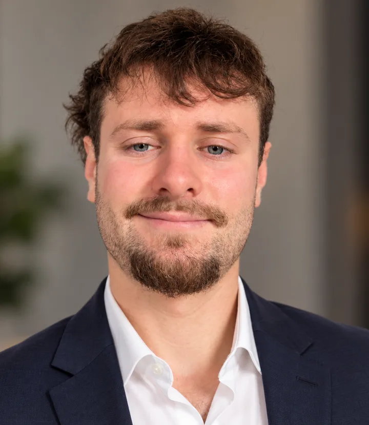Adrien Pouchard, ancien contrôleur de gestion industriel devenu développeur d’agents IA, souriant en veste bleu marine